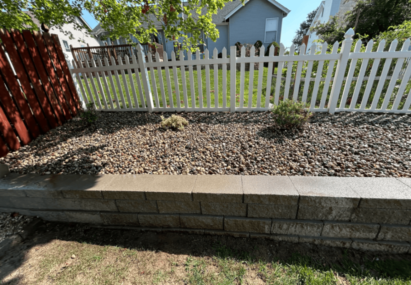 Raised rock garden installation with river rock and clean retaining block edging