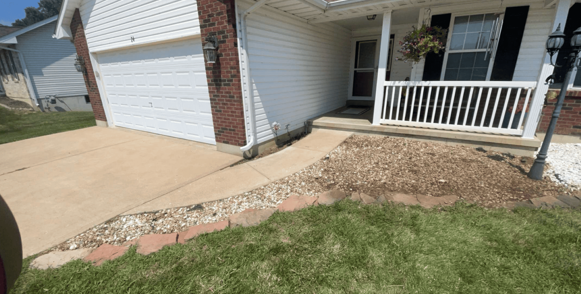 Front yard brown and white decorative rock border installed along a porch and driveway