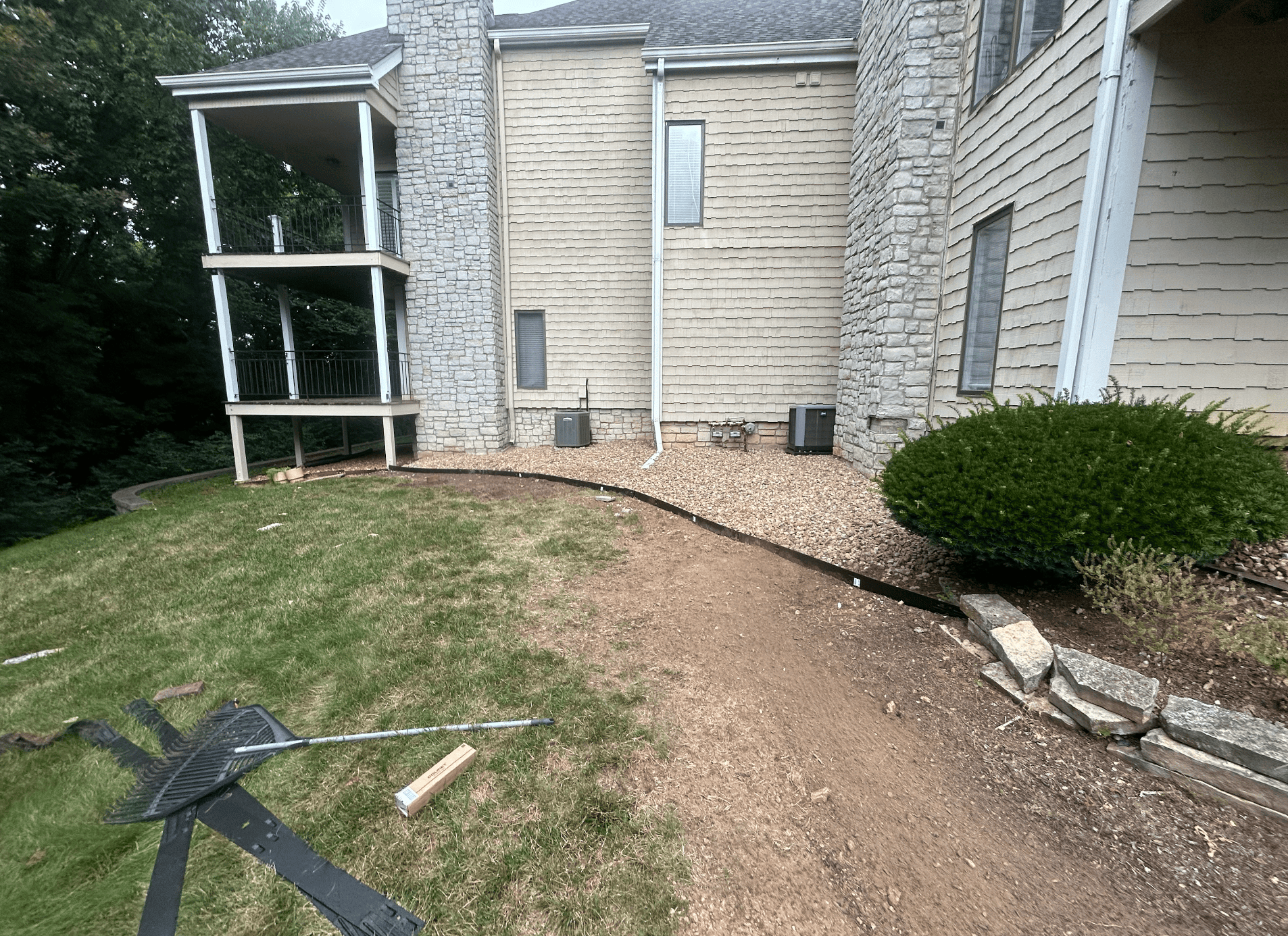 Completed backyard rock bed installation along the rear of a home