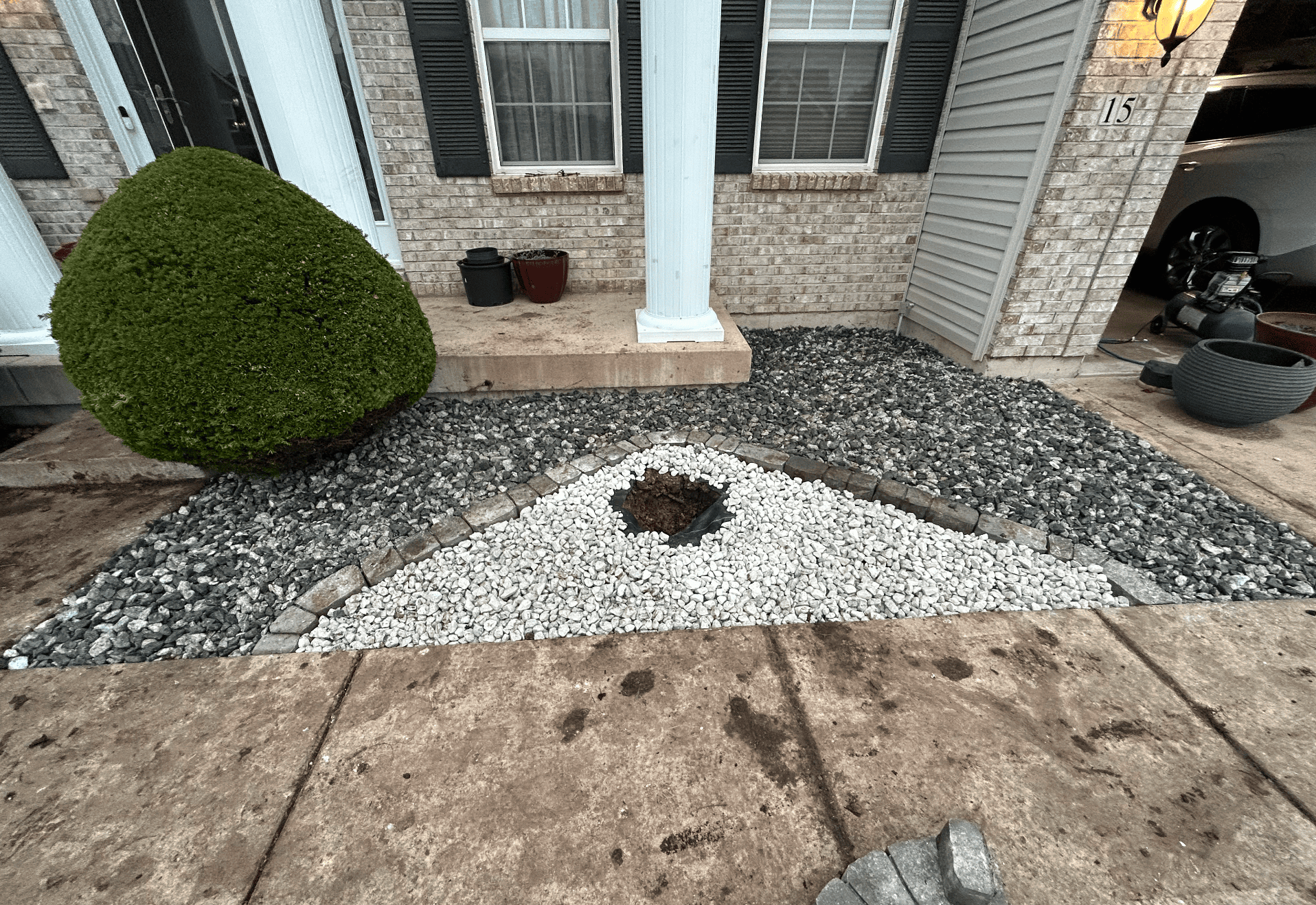 Front entry landscape bed featuring a white triangular rock insert bordered by darker stone